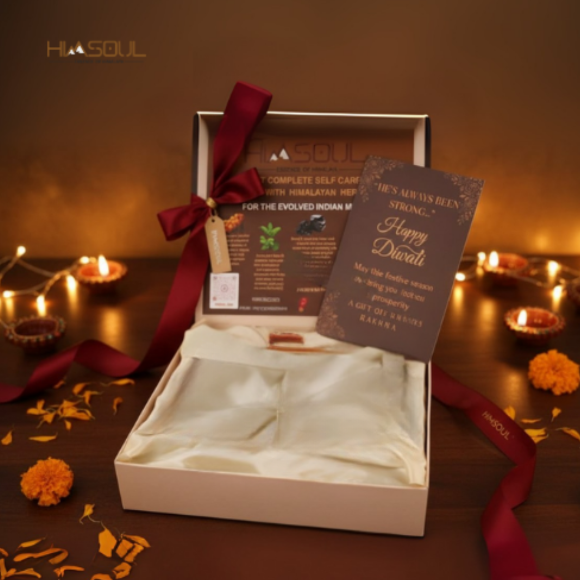 imsoul unboxed Diwali gift box lined with champagne satin fabric, rich crimson ribbon, brass charm, and personalized festive greeting card surrounded by burning diyas.
