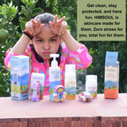 A young girl making playful faces behind a Himsoul Kids product bundle and paper toys, highlighting the "Cut and Glue" creative packaging feature and natural ingredients.