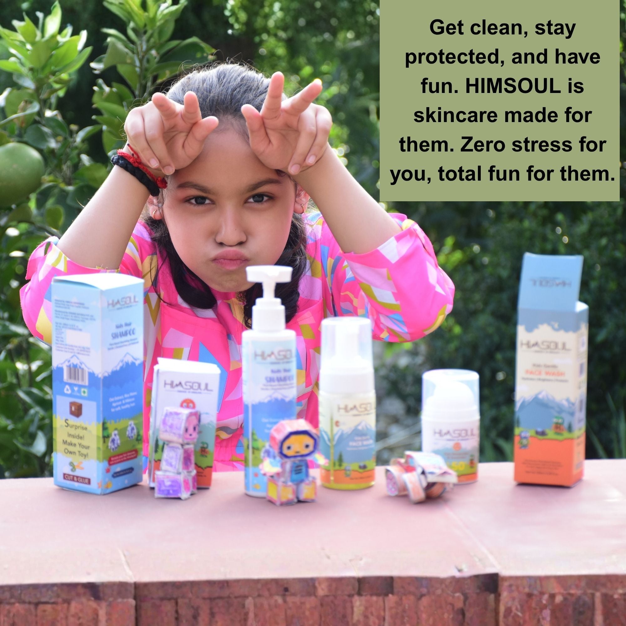 A young girl making playful faces behind a Himsoul Kids product bundle and paper toys, highlighting the "Cut and Glue" creative packaging feature and natural ingredients.